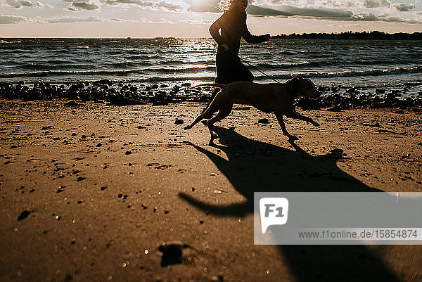 Frau rennt mit Hund am Strand