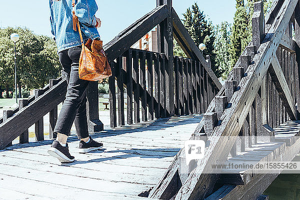 Junge Frau geht auf einer Holzbrücke