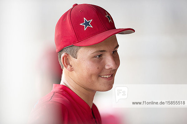 Nahaufnahmeportrait eines jugendlichen Baseball-Spielers in roter Mütze und Uniform