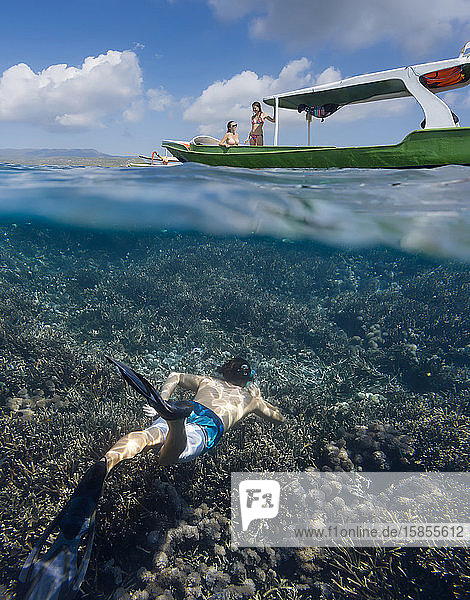 Young man snorkeling near the boat in ocean  underwater view