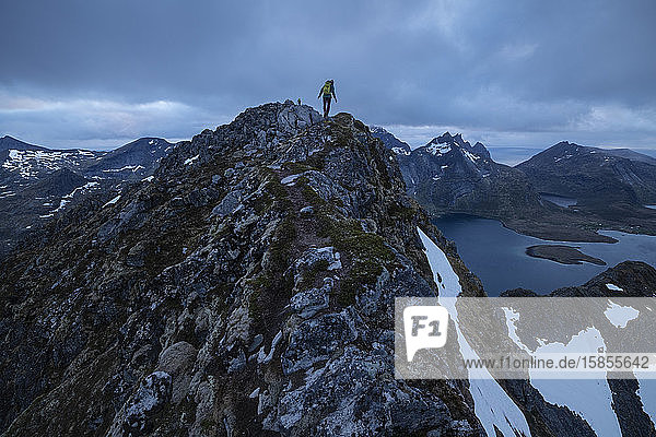 Female hiker on narrow summit ridge of Narvtind mountain peak  MoskenesÃ¸y  Lofoten Islands  Norway