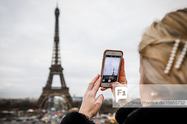 Ein junger Erwachsener macht ein iPhone-Foto vom Eiffelturm in Paris.