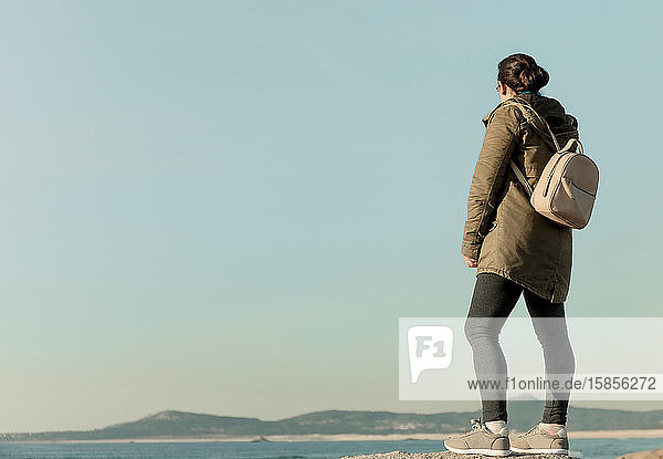 Frau mit Rucksack schaut auf den Horizont über dem Meer