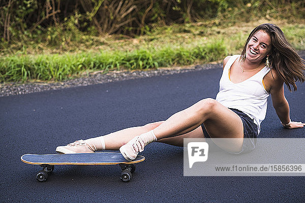 Junge Frau stürzt im Sommer auf ihr Skateboard