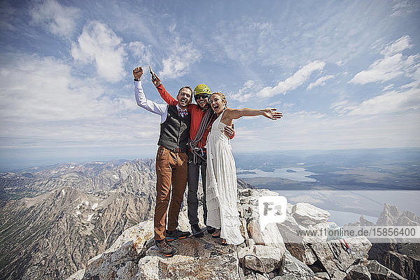 Neuvermähltes Brautpaar feiert mit Kletterführer auf dem Berggipfel