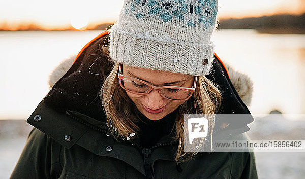 Porträt einer Frau  die im Winter bei Sonnenuntergang mit Schnee im Haar lächelt