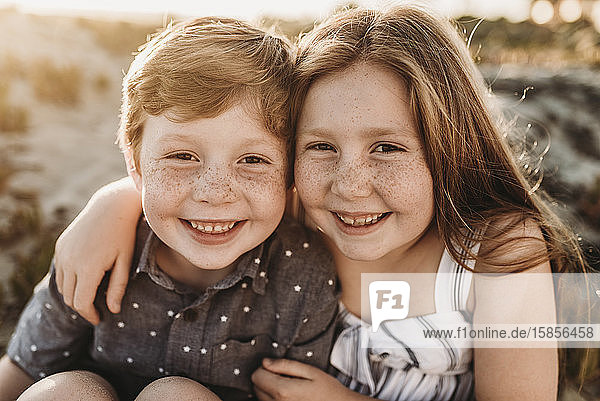 Portrait of young redheaded freckled siblings smiling during sunset
