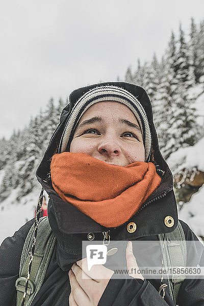 Porträt einer jungen Frau  die im Winter lächelnd und glücklich aufblickt
