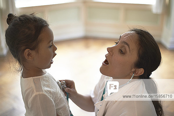 Allgemeinmedizinerin mit Stethoskop bei der Untersuchung eines jungen Mädchens