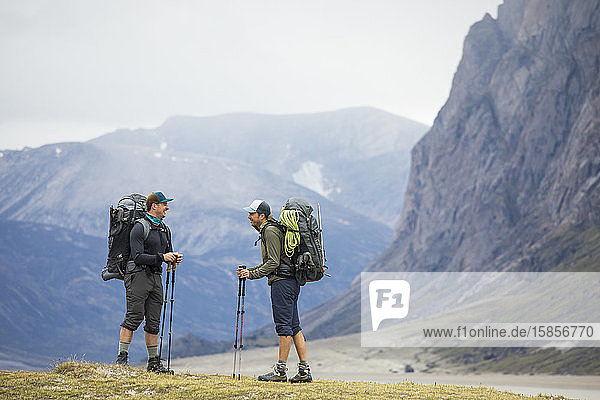 Zwei Freunde halten an  um gemeinsam zu lachen  während sie mit dem Rucksack in den Bergen unterwegs sind.