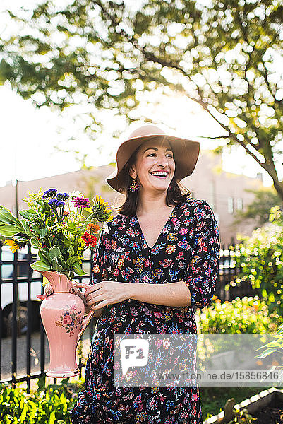 glückliche Frau mit frischen Blumen in städtischer Umgebung