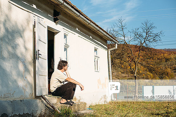Ein Mann  der in der Nähe des kleinen Hauses im Dorf sitzt. Landschaft in den Bergen