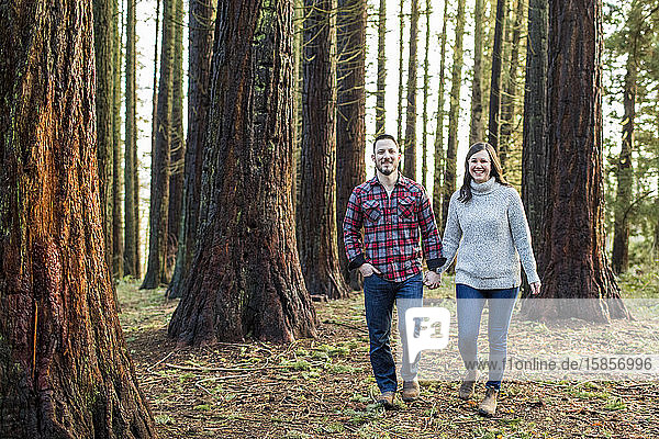 attractive couple walking through forest  looking ahead.