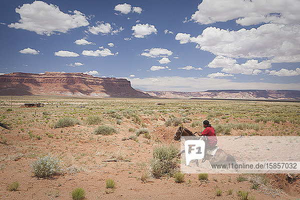 A young man rides a horse across a plain near Monument Valley  Arizona
