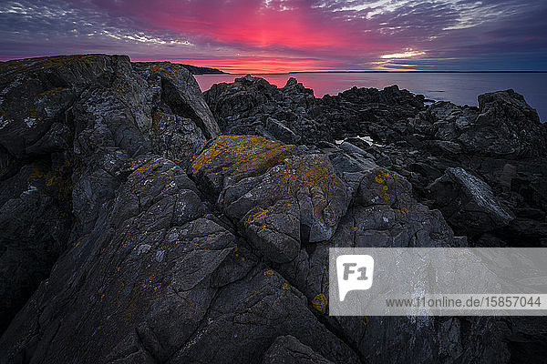 Dramatic red sky at sunrise on the rocky coast of Maine