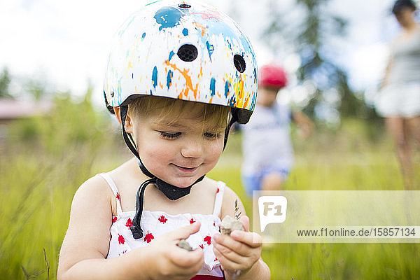 Junges Mädchen mit Helm geniesst Zeit beim Spielen im Freien