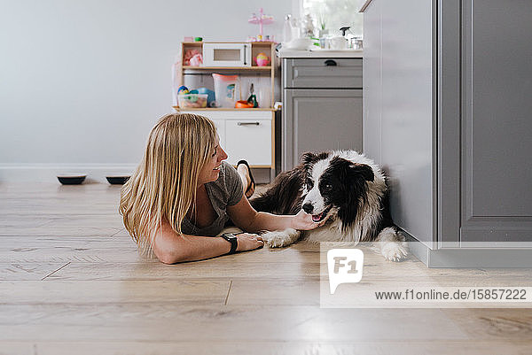 Glückliche Frau lächelt beim Streicheln ihres Hundes zu Hause