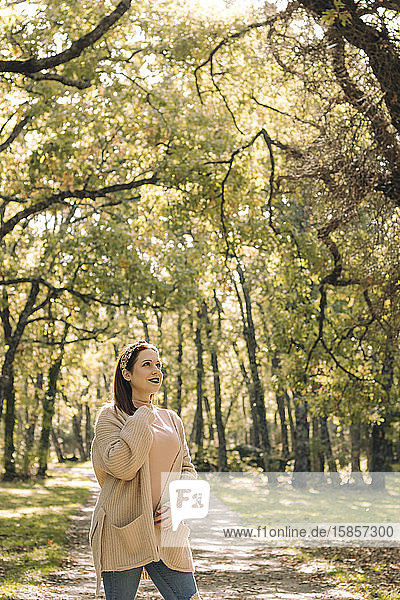 Junge braunhaarige Frau auf einer Straße mitten im Wald im Herbst