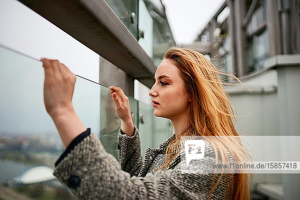 woman holding glass while standing on the balcony