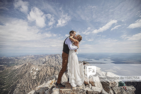 Neuvermähltes Paar bekommt den ersten Kuss während der Hochzeit auf dem Berggipfel von Wyoming.