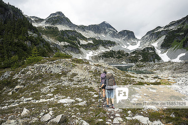 Ein Ehepaar wandert einen Pfad entlang  um eine Nacht in den Bergen zu zelten.