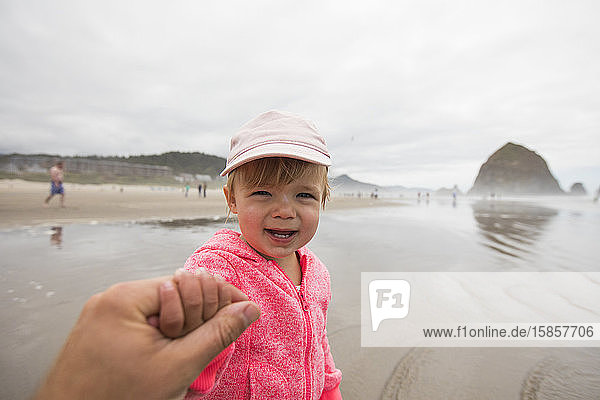 Portrait of young girl holding fathers hand at Cannon Beach.