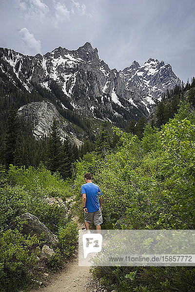 Mann wandert im Sommer auf einem Wanderweg im Teton-Gebirge