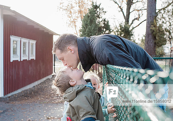 father kissing his son goodbye at the school gate