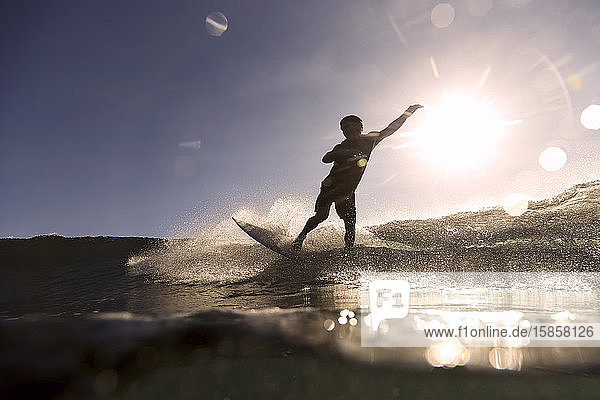Surfer auf einer Welle zur Zeit des Sonnenuntergangs