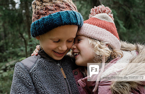 close up of brother and sister hugging and laughing outside