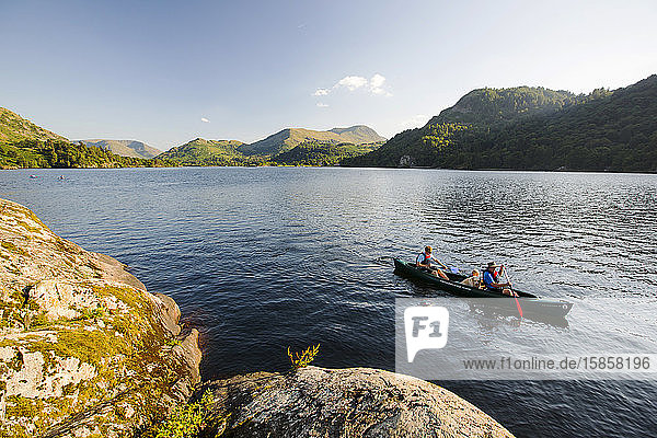 A family paddling in a Canadian Canoe on Ullswater in the Lake District  UK.