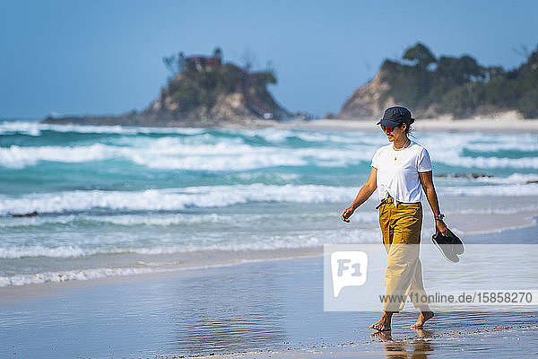 Frau geht barfuss am Strand von Byron Bay / Australien