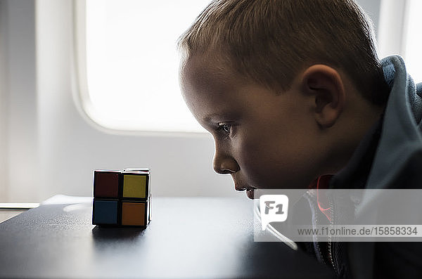 Porträt eines Jungen,  der sich im Flugzeug ein Rubix-Würfel-Spiel ansieht