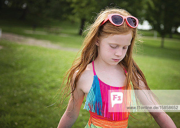 Junges rothaariges Mädchen in Badeanzug und Sonnenbrille