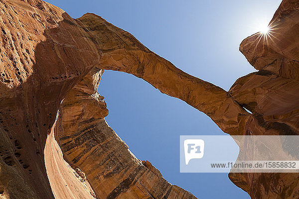 Sandstone rock arch with sunburst against blue sky in Colorado