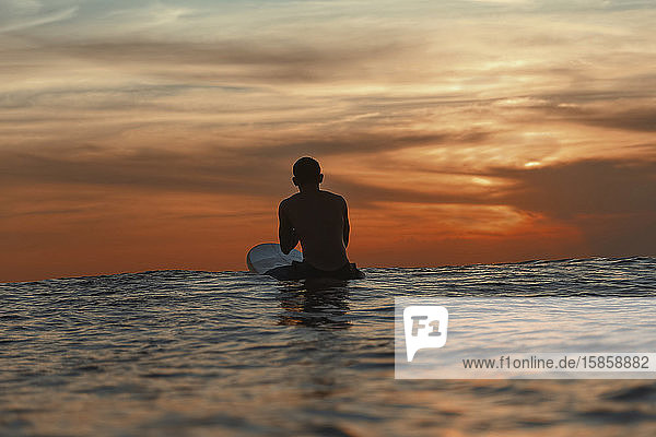 Surfer im Ozean bei Sonnenuntergang