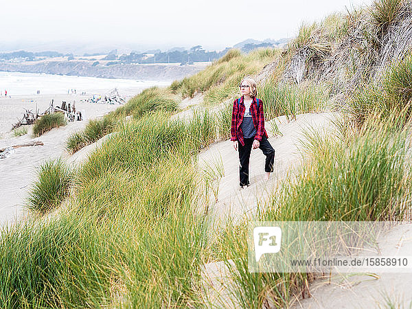 Young boy standing among tall green sea grass on the beach
