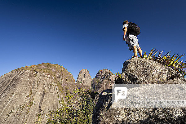 Man posing near dramatic rocky mountain peaks on the rainforest