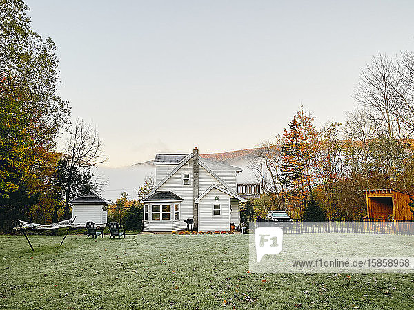 Blick in den Hinterhof auf den gefrosteten Rasen und das Haus mit Bergblick im Herbst