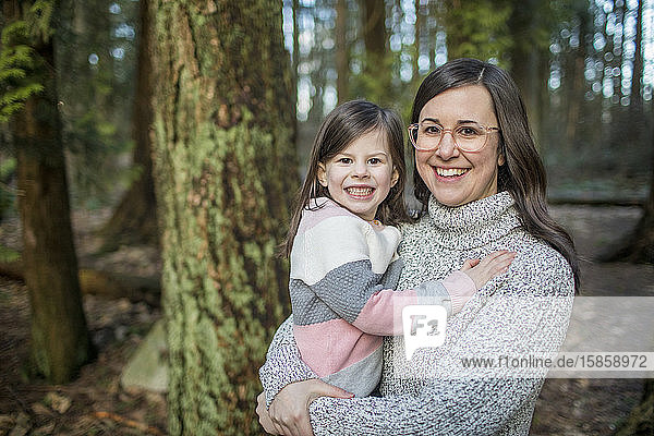 Young mother wearing glasses holds her cute daughter.