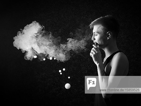 Junger Mann mit Rauch auf schwarzem Hintergrund Vorderansicht