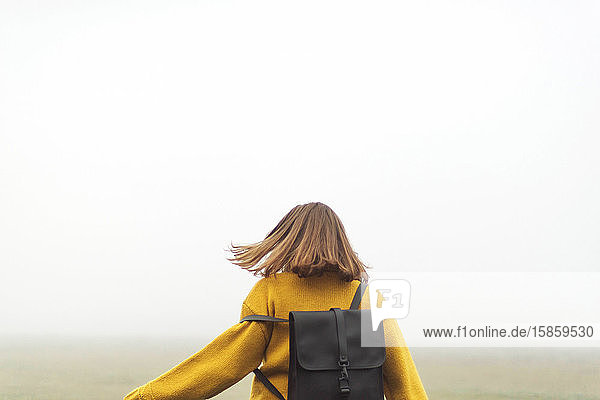 Thoughtful woman standing by forest in foggy weather