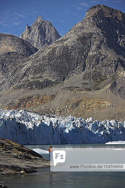 man standing at the water's edge of a fjord in Greenland