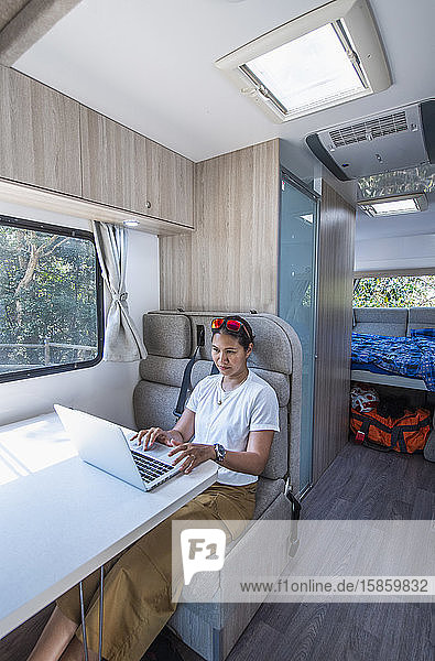 Frau arbeitet an ihrem Laptop in einem Wohnmobil in Australien