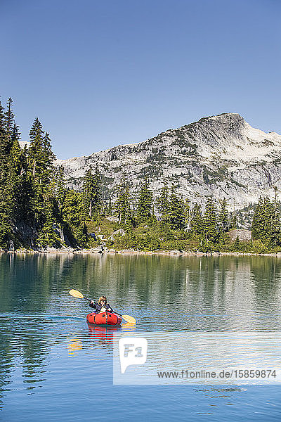Pensionierte Frau paddelt auf einem abgelegenen Bergsee.