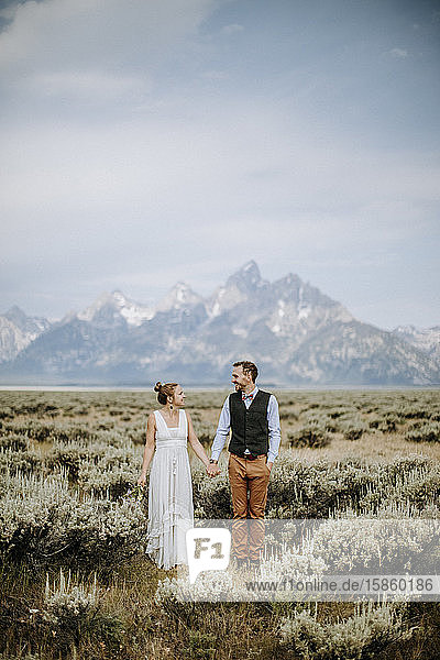 Happy smiling newlywed bride and groom stand in front of Grand Teton