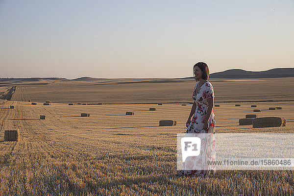 Frau  die das trockene Feld bei Sonnenuntergang beobachtet