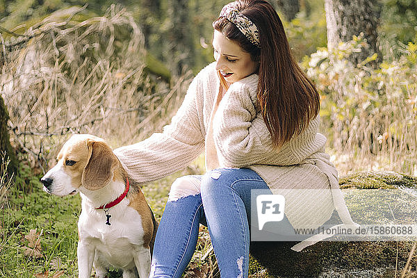 Smiling young woman  sitting next to her dog during a walk