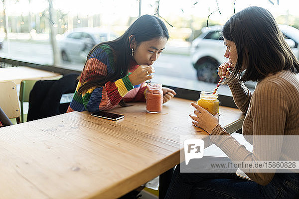 Zwei beste Freunde essen Smoothies in einem Café in der Stadt