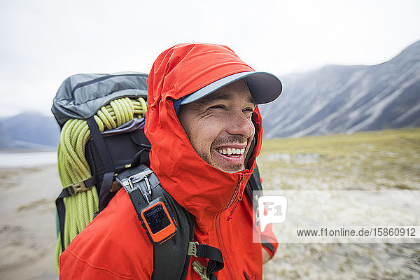 Porträt eines glücklichen Rucksacktouristen mit roter Regenjacke.